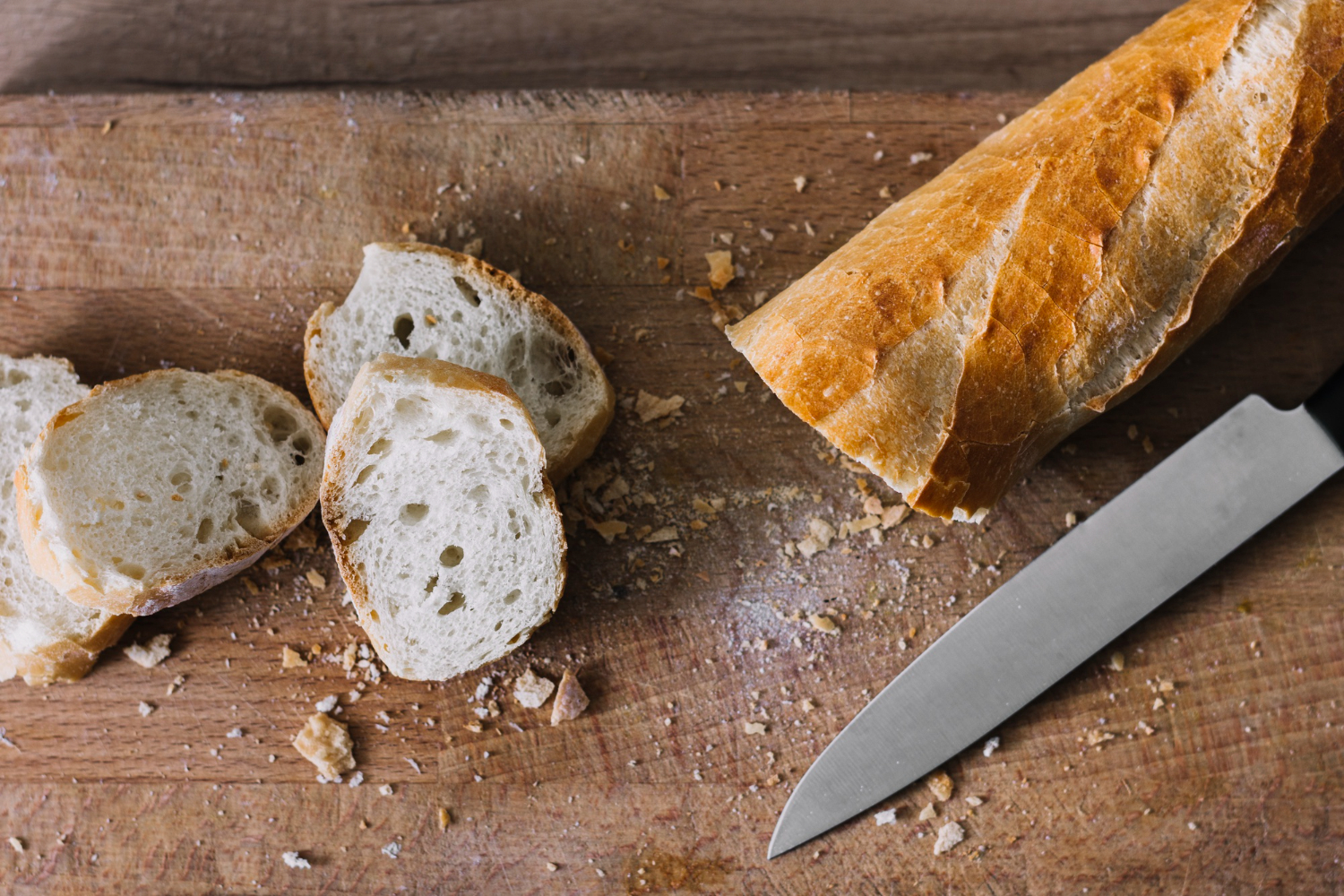 Sliced artisan baguette on a wooden cutting board — a reminder that to increase bakery sales, product quality is just the starting point